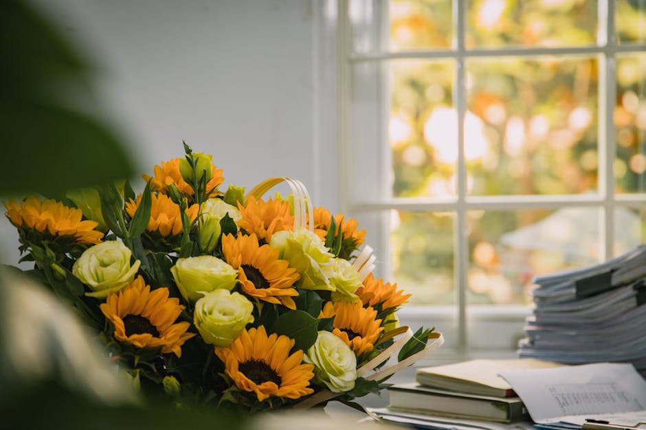 A vibrant floral arrangement featuring fresh sunflowers with bright yellow petals and dark centers, mixed with white roses with soft, layered petals, all nestled in lush green foliage. The bouquet is 